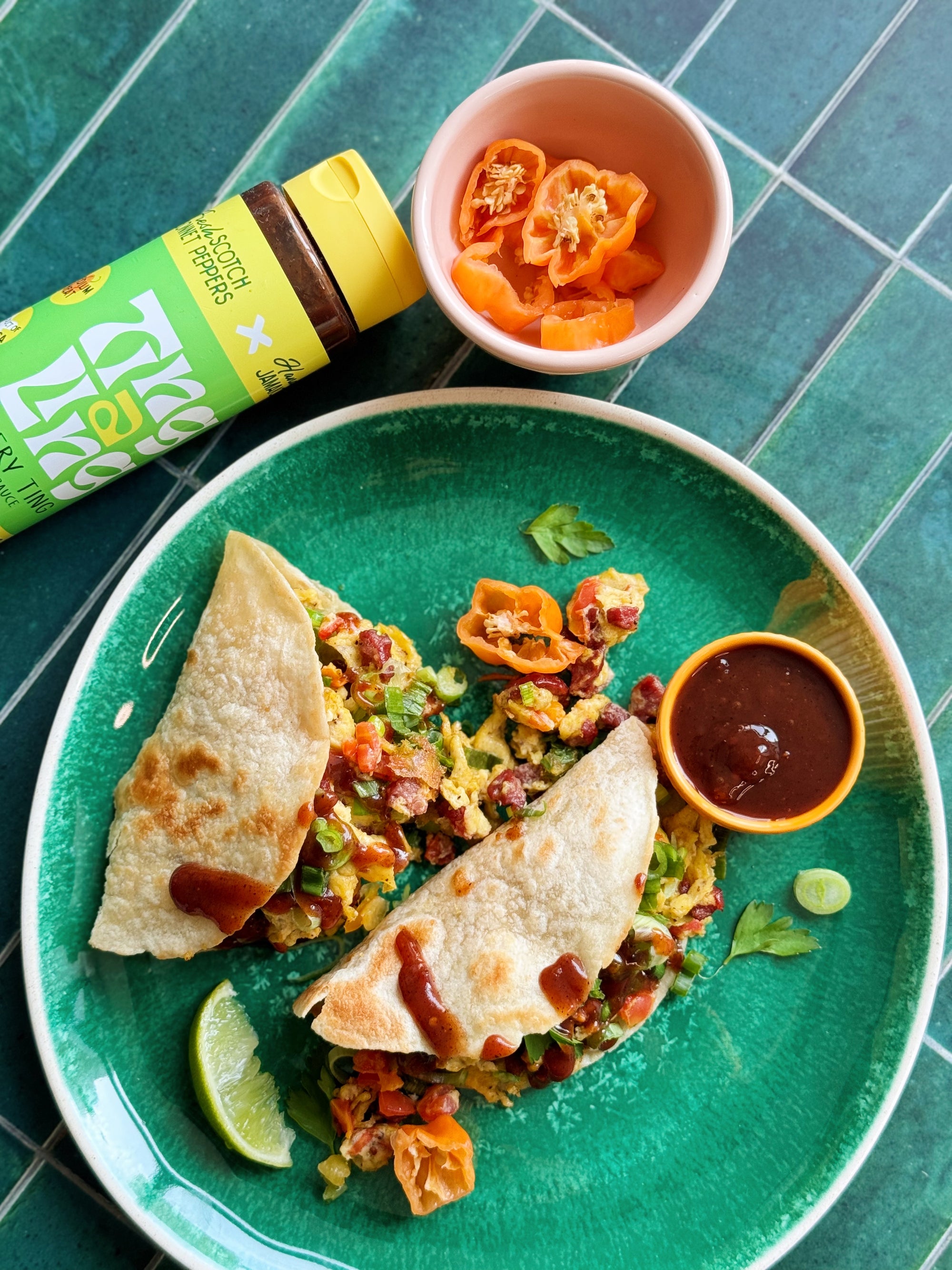 Reggae Scrambled Eggs with sausage, tomatoes, and scallions served on warm tortillas and drizzled with Every Ting Jerk Sauce.